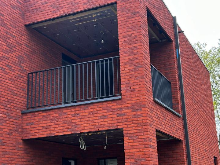 Zwarte balkonbalustrade aan een bakstenen gevel