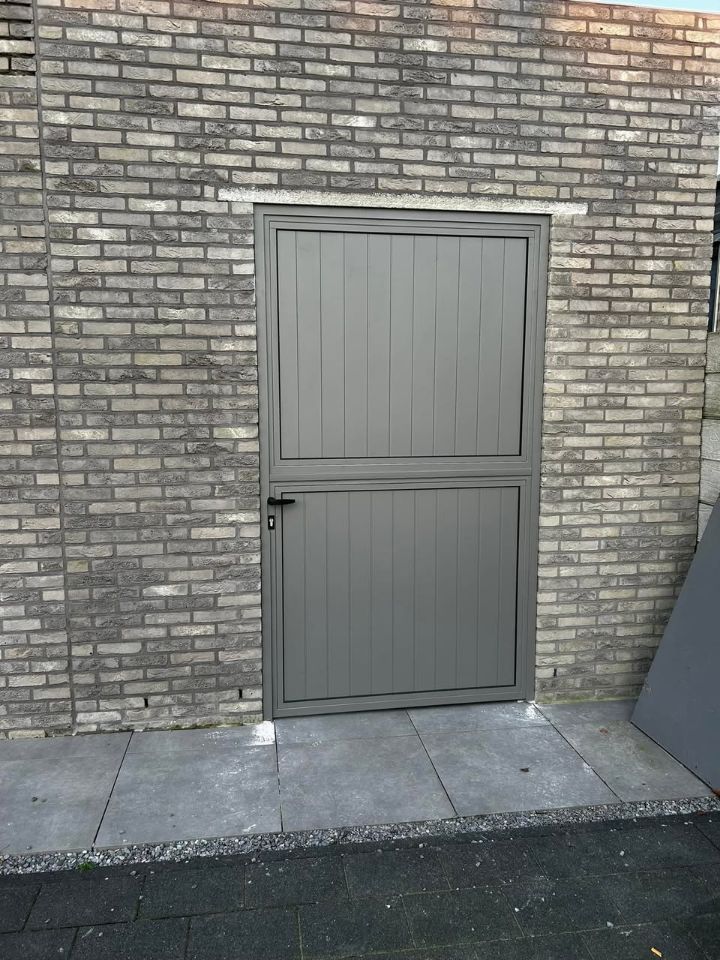 Grijze stalen buitendeur in een bakstenen gevel