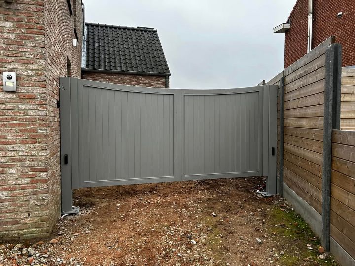 Gesloten grijze poort tussen gevel en houten omheining