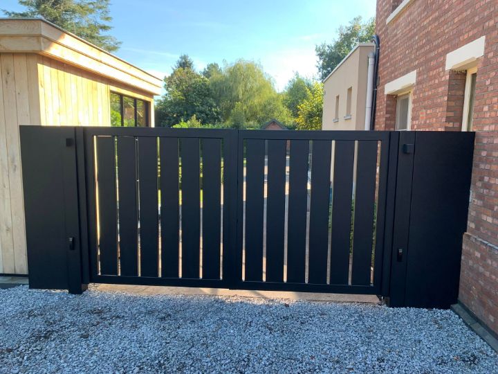 Zwarte poort met verticale latten tussen bakstenen muren